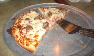 Half-eaten GF sausage pizza at Pizza Luce