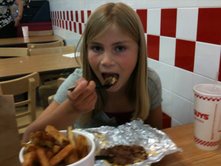 Emma eating her burger at Five Guys Burgers and Fries